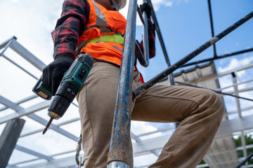 Construction workers wearing safety harness working at high level in the construction site,Roofing tools,Electric drill used on new roofs with Metal Sheet.