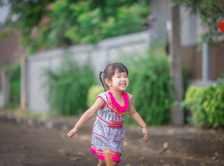 Naklejka premium close-up background view of an asian girl Running around and carrying parasols during school holidays, there was a blur of fun movements during the day with parents.