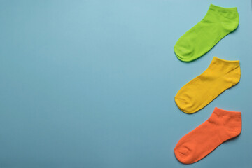 Orange, green and yellow socks on a blue background. Space for the text.