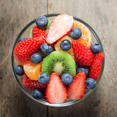 Diet-Fresh tasty mix fruit salad in the bowl on the wooden table, healthy breakfast, weight loss concept.
