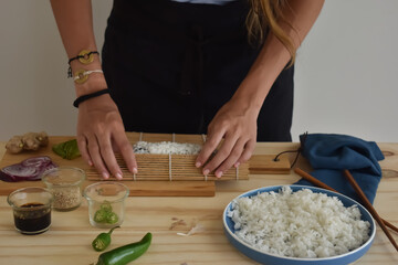 rolling sushi with bamboo tablecloth and previously cooked Japanese rice