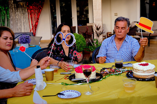 Latino Mexican elderly couple man and woman grandparents bored at family party with party glasses and party props