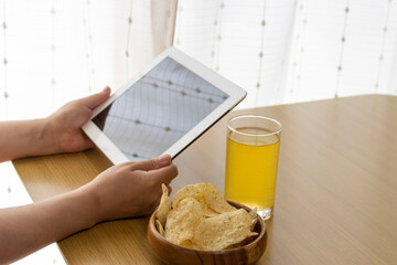 休憩時間におやつを食べ、タブレット端末を使う女性