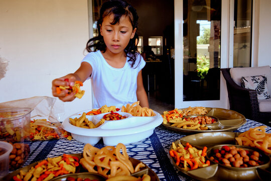 Young Mexican latinx girl helping serving mexican style chips on plates for a party