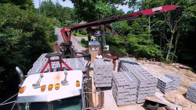 Aerial zoom into cubes of concrete and cinder blocks being unloaded at construction jobsite