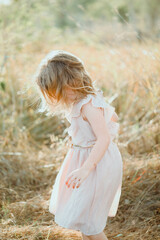 Fototapeta na wymiar Little girl in pretty pink dress playing in natural outdoor setting