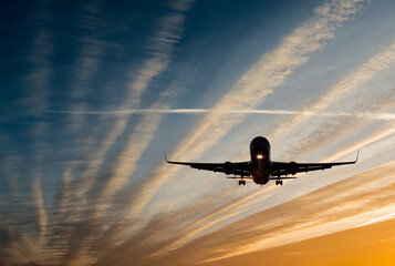 Landing airplane at colorful sunrise with with beams of sun lights. Concept of transport, weather,...