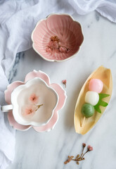 Fototapeta na wymiar Homemade and shop bought snacks and desserts. Sakura Cha with Dango & Caramelised Banana Bread. Japanese mochi with dried sakura flower hot tea.