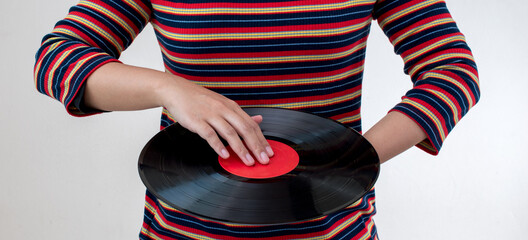 woman wearing colorful striped clothes holding old vinyl retro record music audio on background