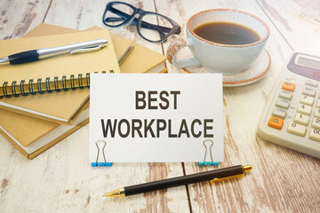 A sign with the inscription BEST WORKPLACE on the table with coffee and notebooks