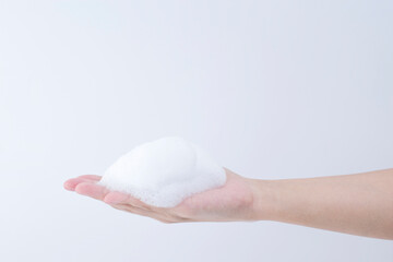 white soapy foam bubbles texture on hand.  cleaning and wash essence facial cleanser background concept