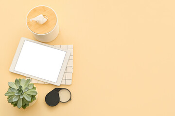 Tablet computer with stationery and tissue box on color background