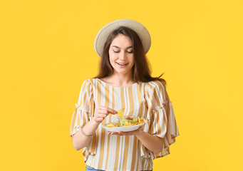 Beautiful young woman eating tasty nachos on color background