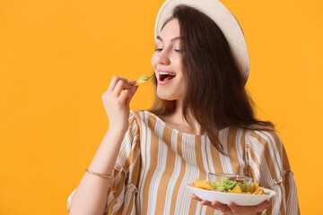 Beautiful young woman eating tasty nachos on color background