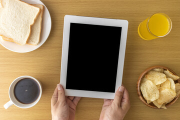 軽食を食べながら、タブレット端末を使う男性の手