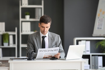 Young businessman reading newspaper in office