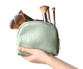 Female hand with stylish cosmetic bag and makeup brushes on white background
