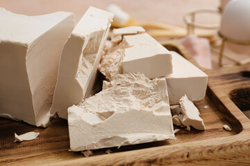 Wooden board with fresh yeast briquettes on table
