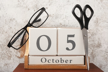 Cube calendar with eyeglasses and scissors on grunge background