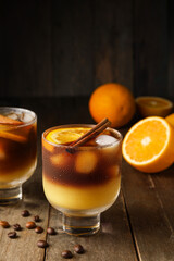 Glasses of tasty coffee with orange juice on wooden background