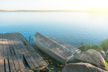Natural autumn landscape with inverted boat on lakes shore. Fishing concept. Rusty ancient boat at...