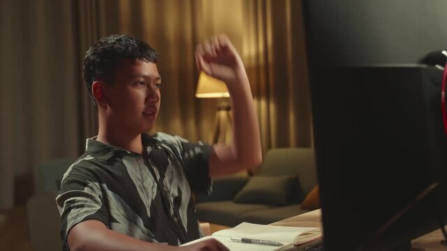 Asian Boy Learning Online From Home, Raising Hand Distance Learning Online While Using Desktop Computer By Video Conference
