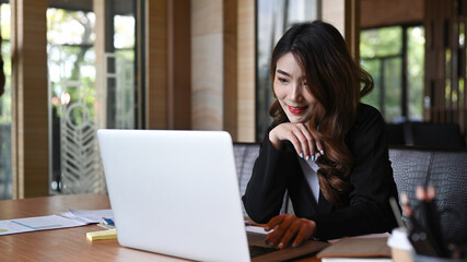 Asian businesswoman working with laptop computer in modern workplace.