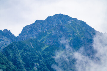 Fototapeta premium 富山県中新川郡上市町の中山から立山の剱岳を望む登山をしている風景 A view of mountain climbing with a view of Tsurugidake in Tateyama from Nakayama in Kamiichi Town, Nakashinagawa County, Toyama Prefecture.