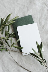 card mockup, olive branch on neutral beige color linen texture background top view.  Space for text. Sheet card template, wedding invitation, menu.