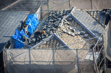 People working to tile a roof damaged by natural disaster