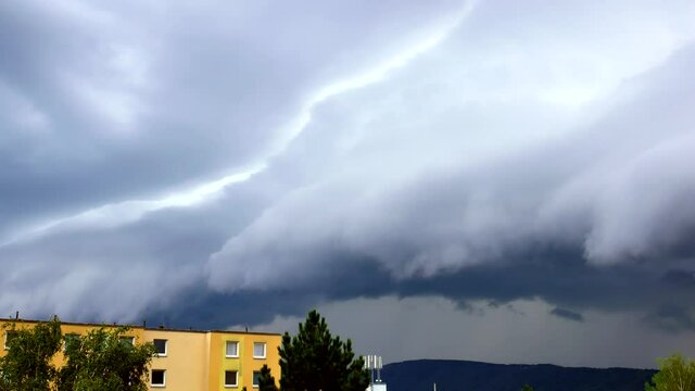 A massive Shelf cloud, Arcus cloud, is slowly moving over the city Usti nad Labem with a lightning strike in the back above the hill