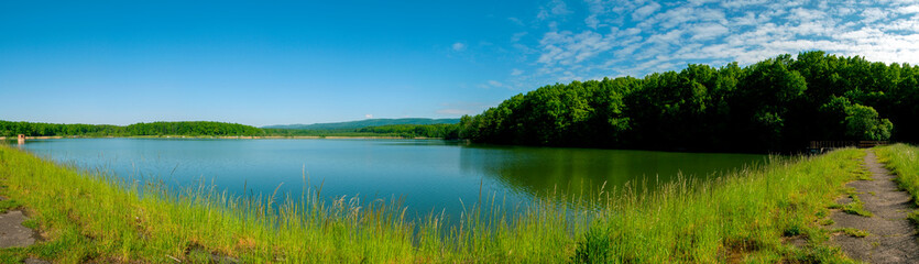Obraz na płótnie Canvas Panoramic view of a calm lake on a sunny summer day