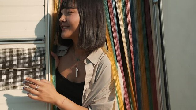 A happy asian woman is coming out from modern caravan trailer