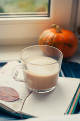 One pumpkin squash and a latte coffee made with with plant based oat soya or almond milk  with blank notepad notebook at the table on the dark black blue textured copy space background work concept