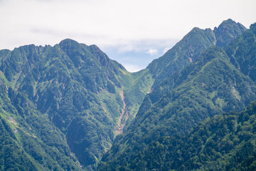 Fototapeta premium 富山県中新川郡上市町の中山から立山の剱岳を望む登山をしている風景 A view of mountain climbing with a view of Tsurugidake in Tateyama from Nakayama in Kamiichi Town, Nakashinagawa County, Toyama Prefecture.