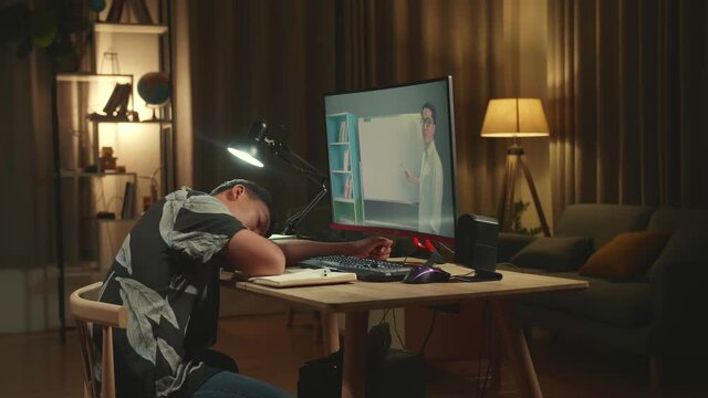 Tired Teenage Boy Sleeping On The Table While Distance Learning With Online Teacher On Computer Screen From Home
