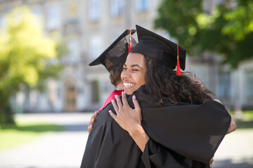 Friends hugging each other after graduation and feeling happy