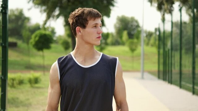 An athlete guy is coming to basketball playground outdoors