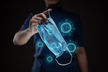 Close up shot of hands holding protective face mask with virus hologram effect.