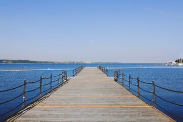 Obraz premium The pier near beach against blue sky in sunny day. Adriatic coast and sea in Slovenia. Holiday and travel concept. 