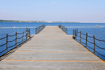 Obraz premium The pier near beach against blue sky in sunny day. Adriatic coast and sea in Slovenia. Holiday and travel concept. 