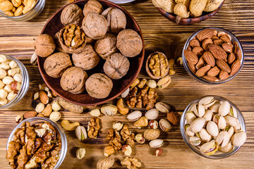 Various nuts (almond, cashew, hazelnut, pistachio, walnut) in bowls on a wooden table. Vegetarian meal. Healthy eating concept. Top view