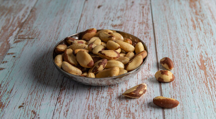Natural Brazil nuts in a bowl on a wooden table, healthy fat and protein food, vegan, ketogenic nutrition concept