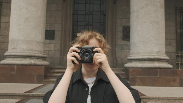 A young girl photographer walks around the city and takes photos on a retro camera. High quality 4k footage