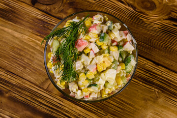 Salad with crab sticks, boiled eggs and cucumbers on a ceramic plate