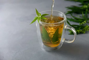 Selbstklebende Fototapeten Cup of hot herbal cannabis or hemp tea in glass mug © molenira