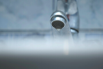 Dripping old faucet in bathroom. Water dripping from a tap into white sink, close-up bottomview....