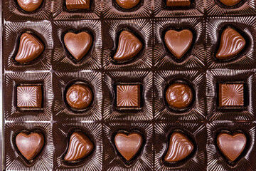 Heap of chocolate candies in a brown box. Top view