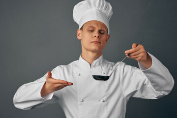 chef in a white robe with a ladle in his hands cooking food restaurant