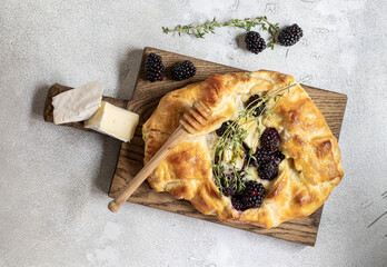 Baked brie cheese and blackberry open pie galette with thyme and honey. Homemade puff pastry...